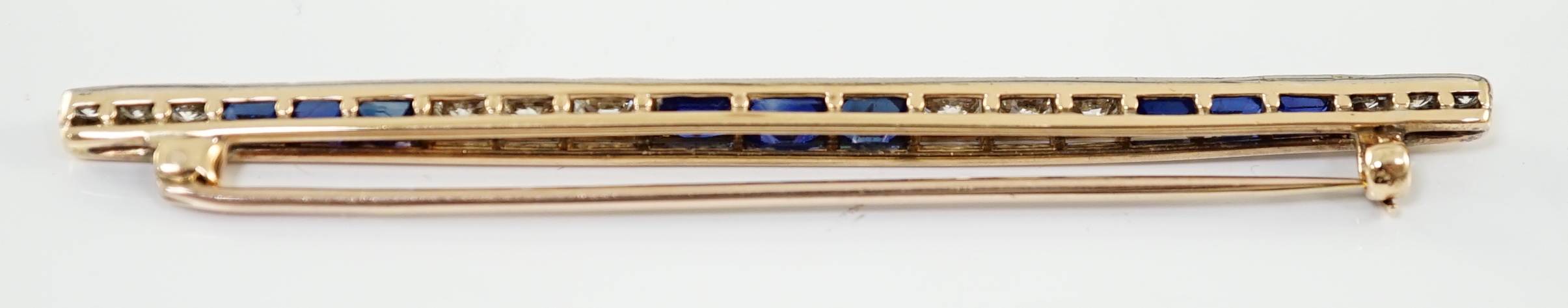 An Art Deco, round cut diamond and rectangular cut sapphire cluster bar brooch